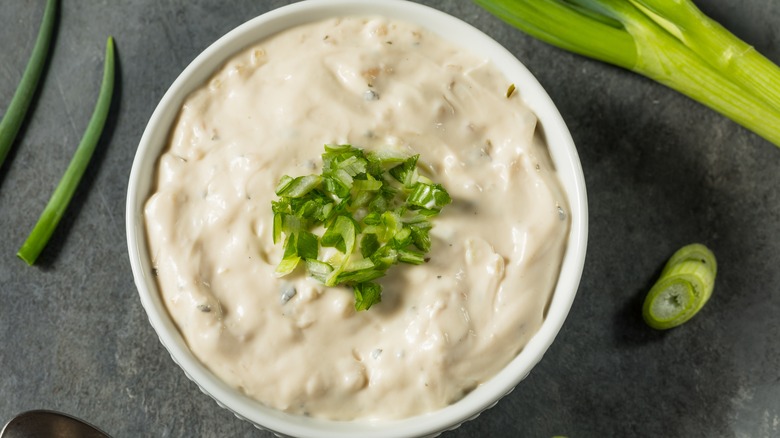 bowl of french onion dip surrounded by green onions