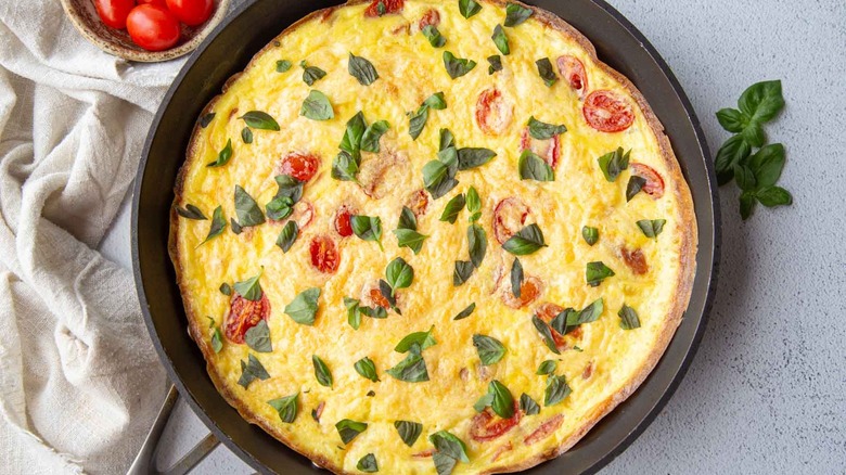 basil, tomato, and prosciutto frittata in a cast iron skillet