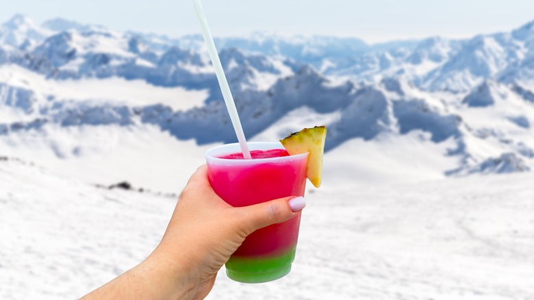 holding out drink against snowy backdrop