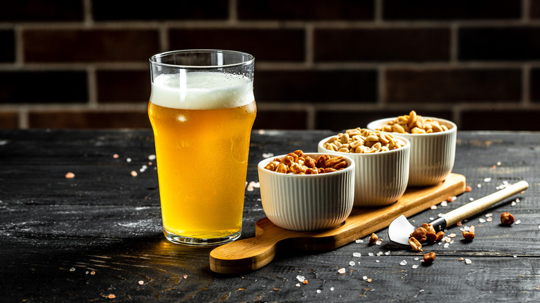 beer and peanuts with dark brick background