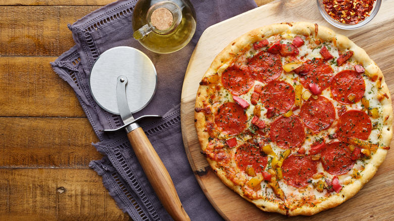 Pizza cutter and pizza on table