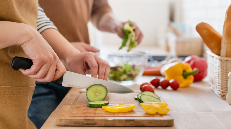 woman cutting vegetables on a wood cutting board