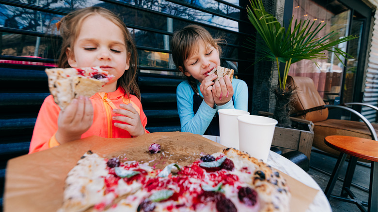 Two children eating berry pizza