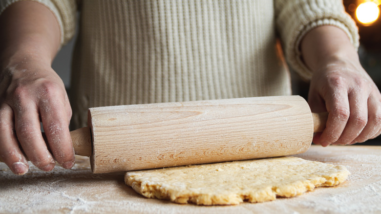 Person rolling dough with rolling pin