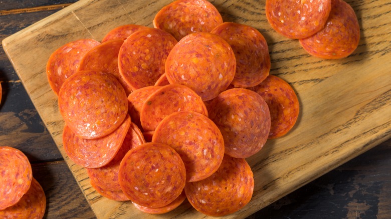 Pepperoni slices on wooden cutting board