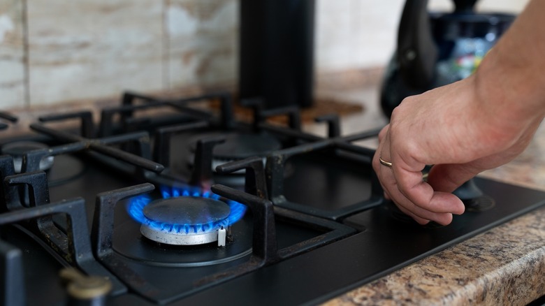 person lighting a home gas stove