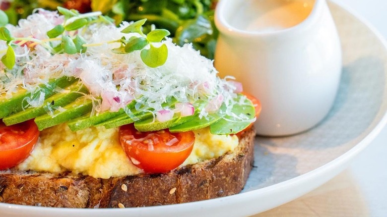 de laurentiis's cacio e pepe eggs topped with avocado and tomato