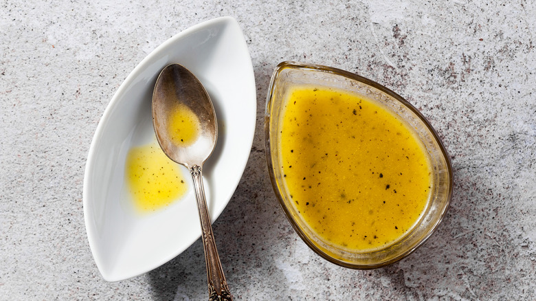 glass bowl filled with vinaigrette next to spoon resting on dish