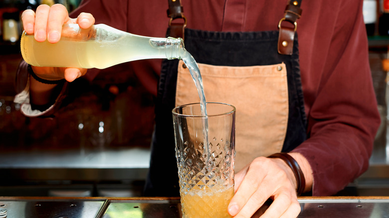 bartender pouring ginger beer in glass