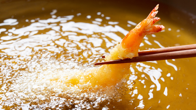 frying shrimp in oil with chopsticks