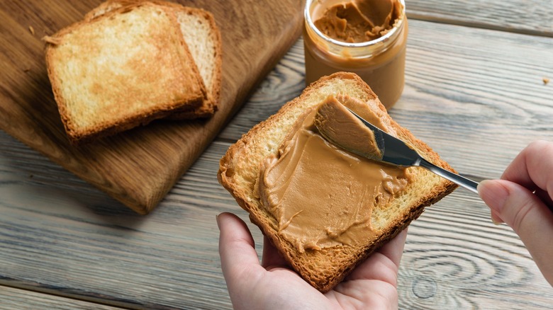 Spreading peanut butter on bread