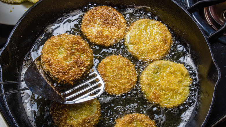 Fried green tomatoes cooking in a cast iron skillet