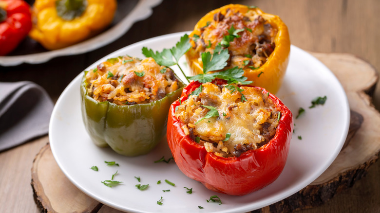 Three baked stuffed peppers on a plate garnished with parlsey.