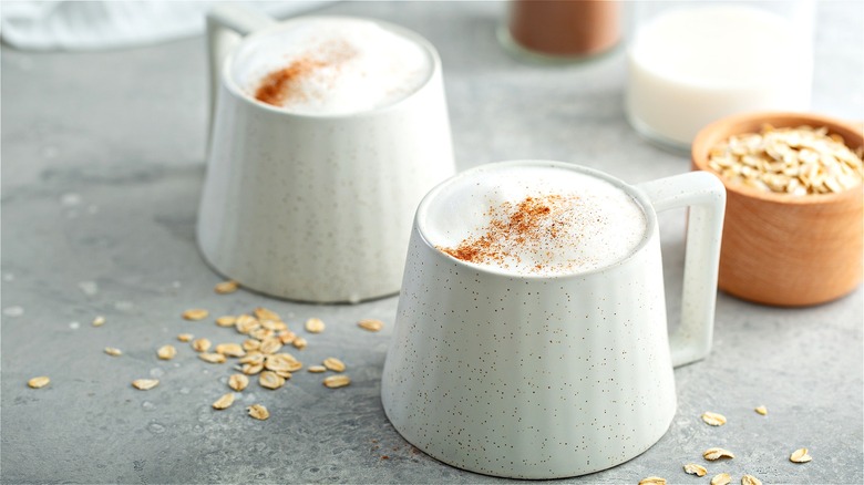 Frothy milk beverages in mugs 