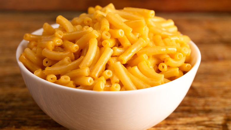 classic macaroni and cheese in white bowl on wooden counter