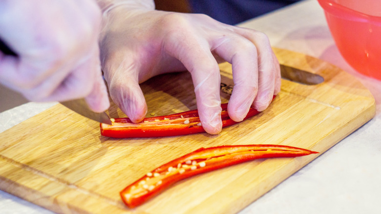 Person slicing peppers wearing gloves