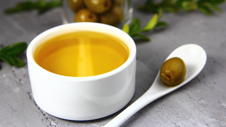 Olive oil ramekin with olive on spoon