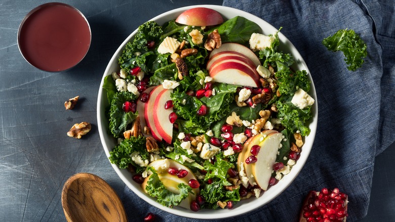 Apple pomegranate kale salad next to dressing