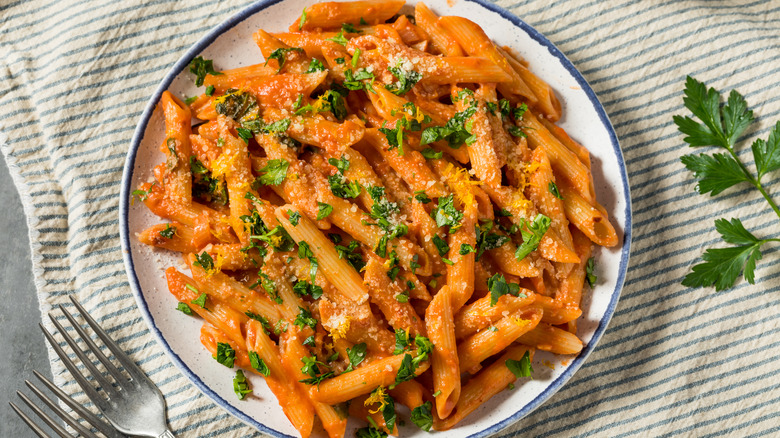 Penne alla vodka on plate with forks and herbs