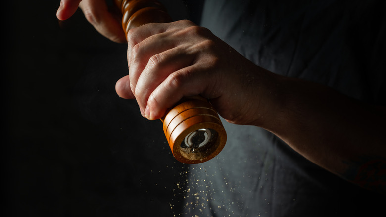 Chef grinding pepper with mill