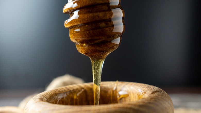 Honey dripping from wooden dipper