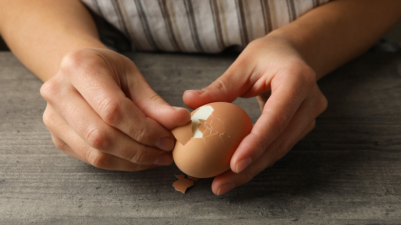 A woman peeling an egg