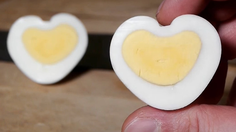 Person holding heart shaped boiled egg