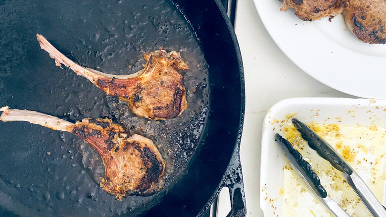 lamb chops cooking in cast iron pan