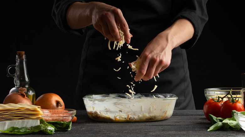 Chef putting cheese into lasagne