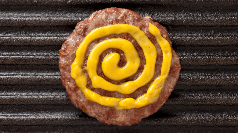 Mustard on a burger on the grill