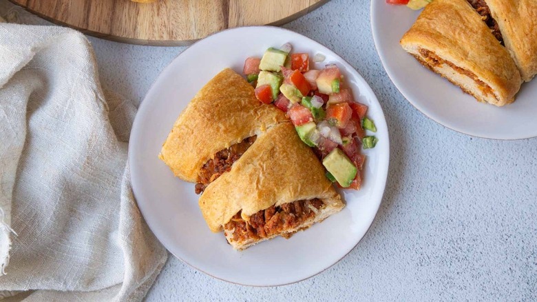 meat-filled bread on white plate with salsa