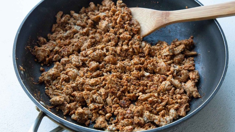 ground meat in frying pan with wooden spatula