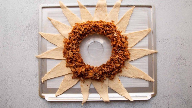 crescent rolls and cooked ground meat arranged in ring on baking sheet