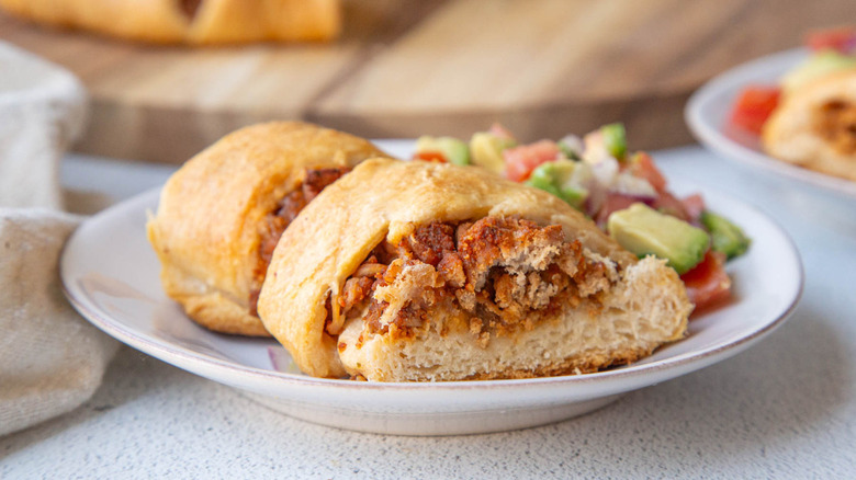 meat-filled bread on white plate with salsa