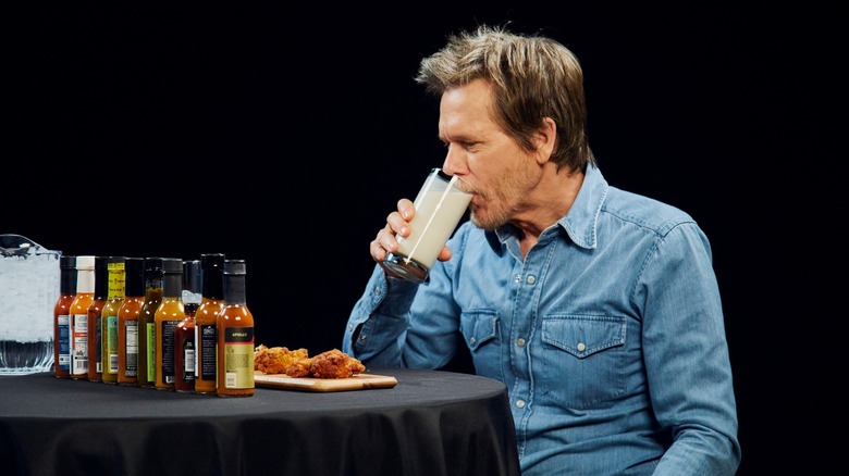 Kevin Bacon drinking milk next to hot sauces