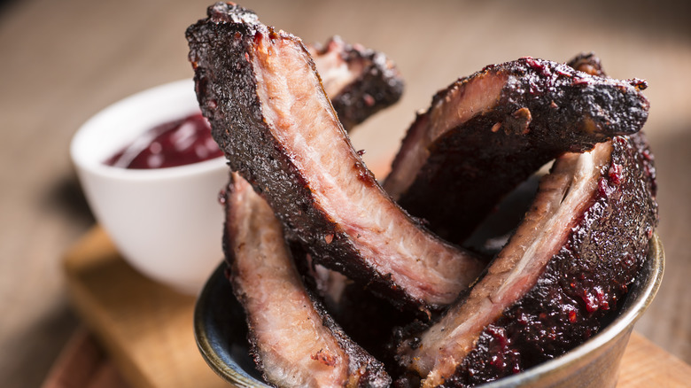 Cut smoked ribs in a bowl with bbq sauce on the side