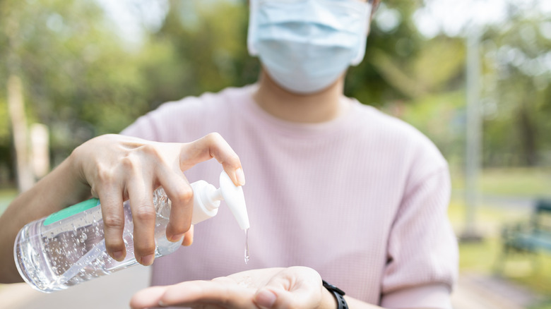 Masked person using hand sanitizer