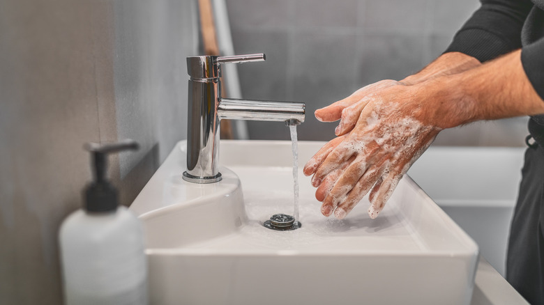 Washing soapy hands in sink