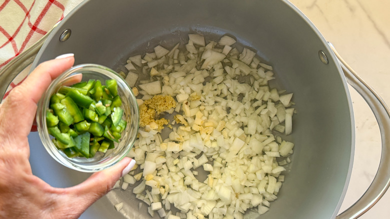 hand adding jalapeno to pot