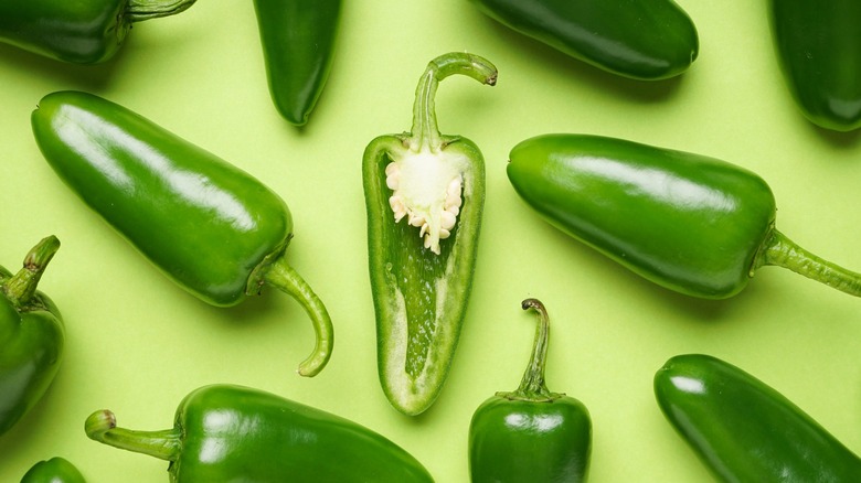 Top-down view of a sliced jalapeño pepper with whole peppers