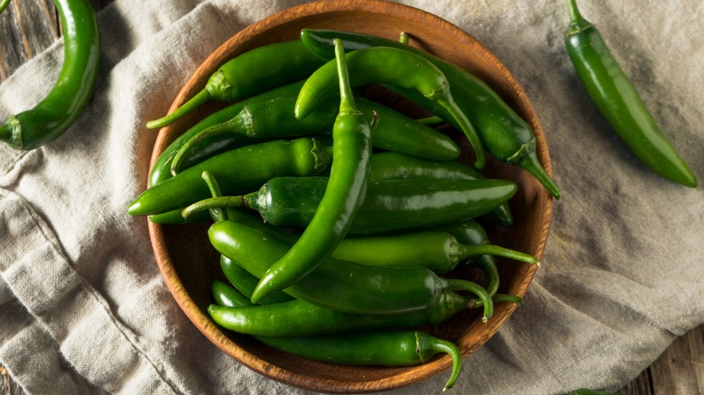 Top-down view of a bowl of fresh green serrano peppers