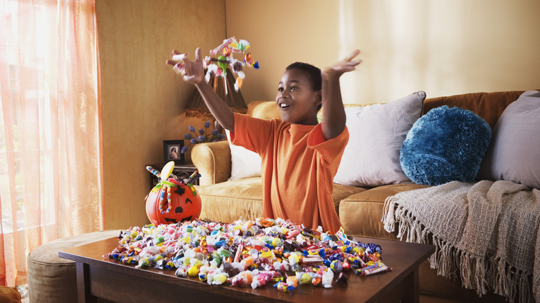 Child joyfully tossing a handful of Halloween candy in the air