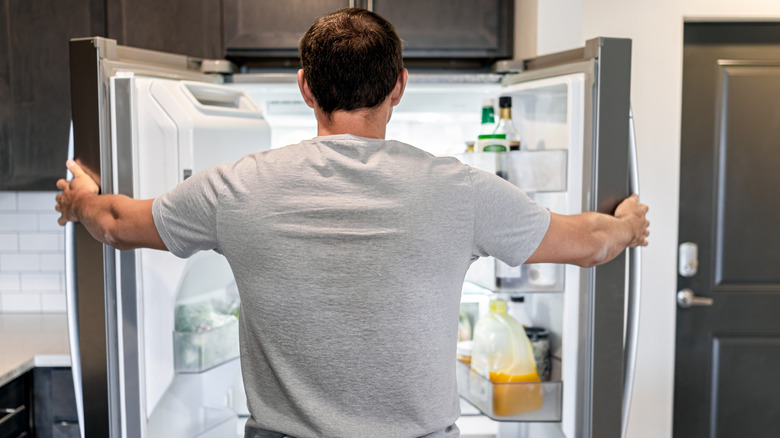 man looking into refrigerator