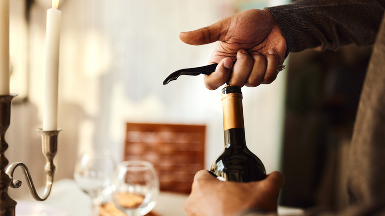 man opening bottled of wine