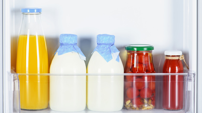 jar of juice milk and vegetables in fridge door