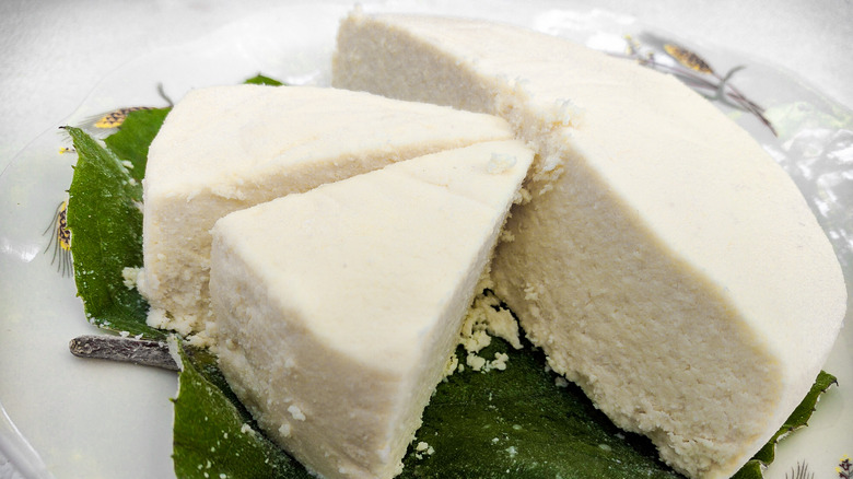 Queso fresco wheel on plate of greens