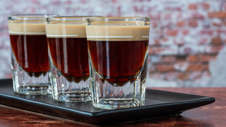 Three shot glasses with coffee liqueur lined up in a row.