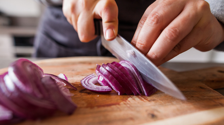 person chopping onion on board