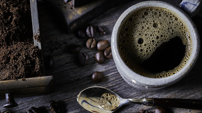 Coffee cup with spoon and whole beans and grounds