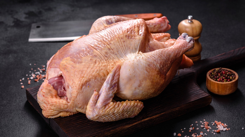 whole raw turkey on cutting board with seasonings